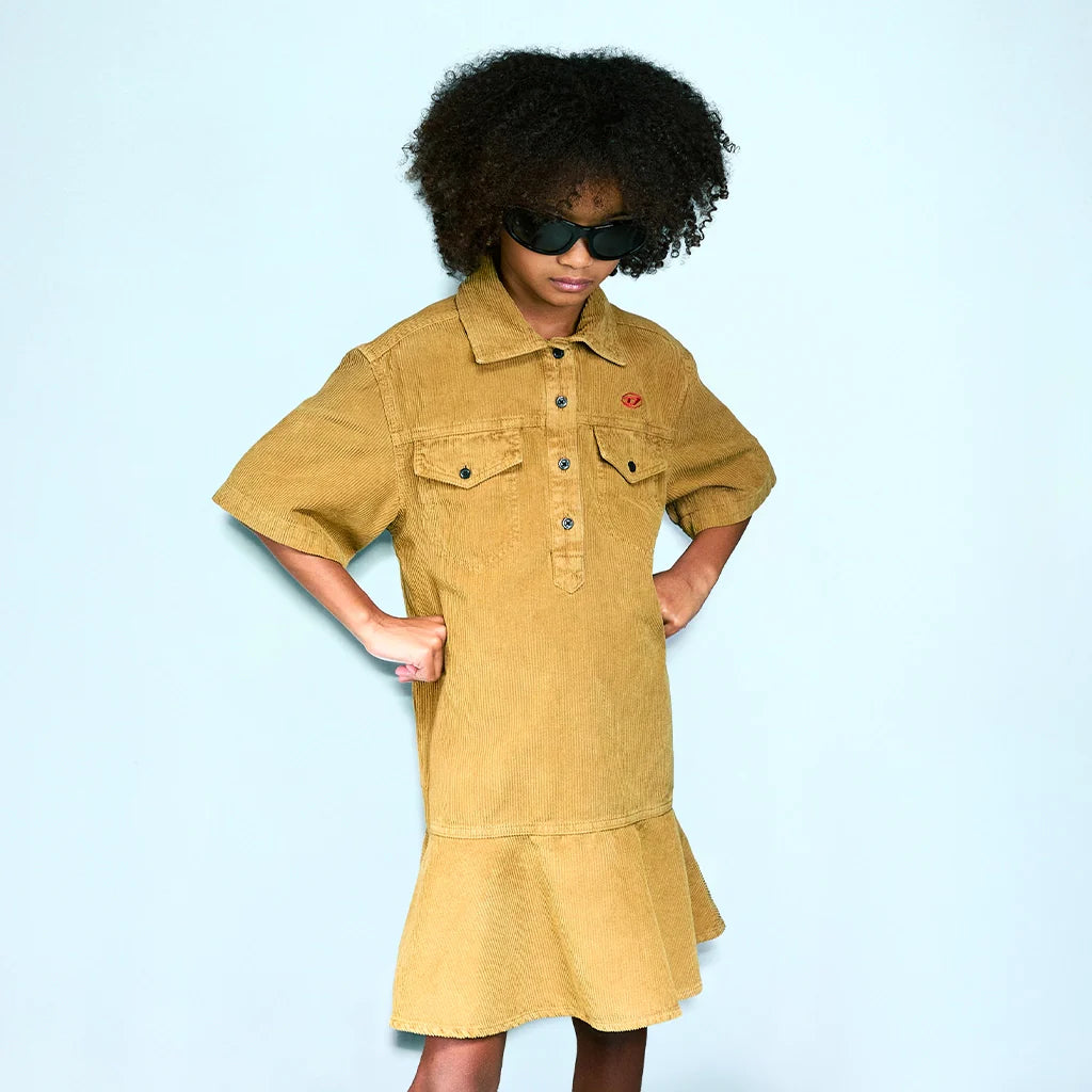 A girl posing with a yellow denim dress, against a light-blue background