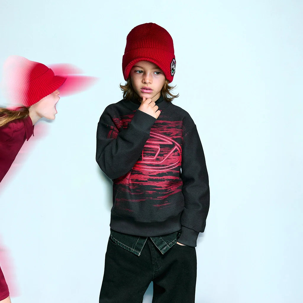 A child model wearing a red hat and a cool outfit, set against a light-blue background.
