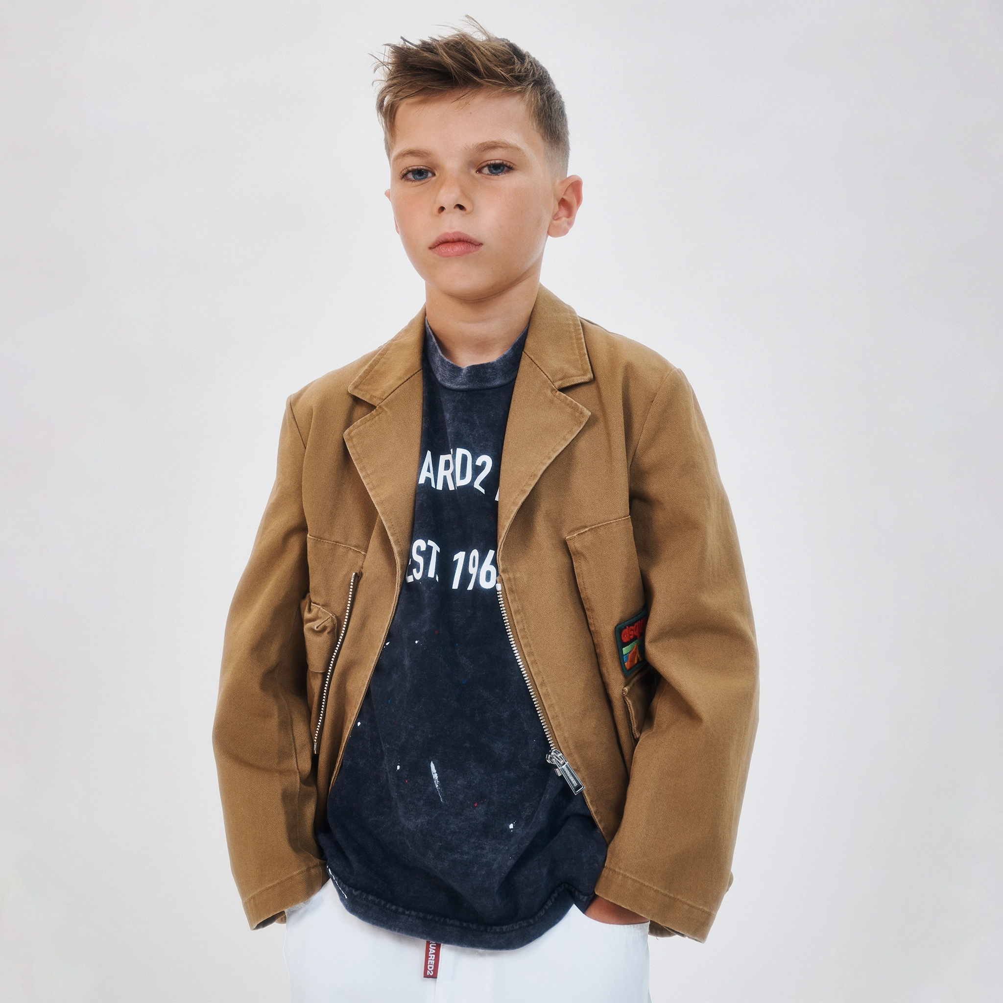 A boy with a stylish look, including a jacket 